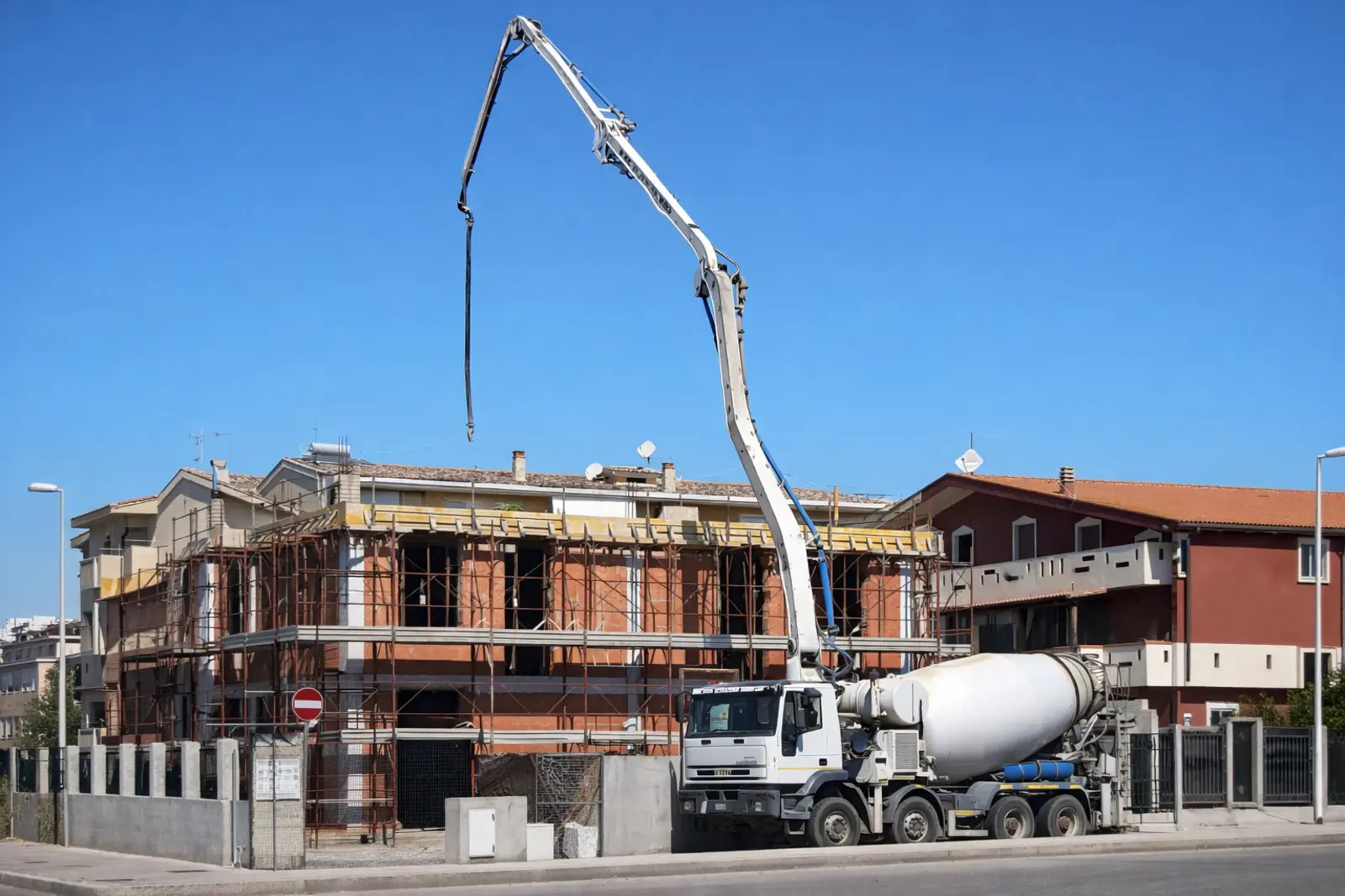 NorDomus building under construction in Sardinia with concrete mixer truck and crane